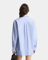 Camisa celeste con rayas verticales blancas, de corte amplio y manga larga.