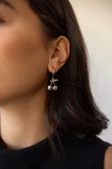 Par de aros plateados con forma de cerezas colgando de un aro pequeño.