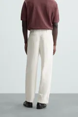 Pantalón de vestir color blanco hueso, de corte relajado (relaxed fit) y tejido de algodón con textura espiga. Presenta bolsillos frontales, bolsillo cerillero y bolsillos traseros de vivo.