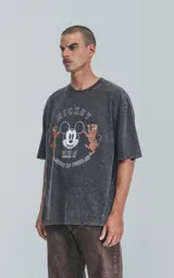 Remera de algodón premium, color negro con efecto nevado (acid wash), corte oversize y cuello redondo. Presenta un estampado frontal con la cara de Mickey Mouse, dos tigres y texto en inglés y chino que incluye "MICKEY", "WONDER-FUL" y "SPIRIT OF TIGER".