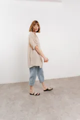 Camisa color beige de lino, con corte recto y calce suelto, cuello camisero, botones en el frente y mangas cortas con presilla y botón.