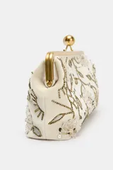 Bolso de mano tipo clutch color crema, con cierre metálico dorado y apliques florales bordados con lentejuelas y cuentas plateadas, doradas y negras.