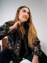 Chaqueta negra con bordados florales de colores, corte recto y cuello mao.