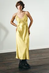 Vestido midi amarillo satinado con escote en pico, tirantes finos ajustables y detalle de encaje a tono en el escote y laterales.