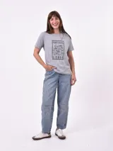 Remera blanca de algodón con cuello redondo y manga corta. Presenta un pequeño bordado en el pecho izquierdo con una figura que parece ser una persona acostada en una tabla de surf o flotador.