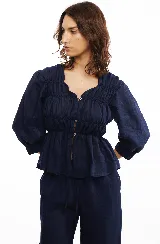 Blusa azul marino de lino con frunces en el delantero y espalda, cierre frontal con botones de nácar y mangas largas con puños elásticos.