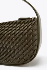 Bolso de mano color verde militar con efecto trenzado y asa corta. Incluye correa extraíble para usar como bandolera y cierre de cremallera metálica.