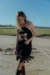 Top strapless negro confeccionado en gamuza con apliques geométricos de cuero en tonos beige y marrón. Presenta flecos en el ruedo.