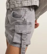 Minifalda de jean con efecto mármol, trabillas en la cintura, bolsillos cargo laterales con lazo y hebilla.