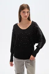 Sweater negro de tejido acanalado, corte holgado tipo murciélago con mangas largas ajustadas en puños. Escote bote adornado con apliques de pedrería plateada que se extienden por los hombros y mangas.