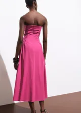 Vestido midi fucsia sin mangas, con escote recto, detalle fruncido en los laterales y cierre de cremallera en la parte posterior.