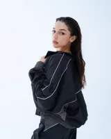 Campera deportiva bomber negra con recortes y vivos blancos.