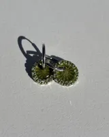Par de aros colgantes con dije circular de resina color verde y borde de strass plateado. El arito es de acero quirúrgico.