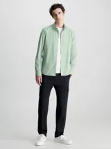 Camisa verde claro de popelín elástico, corte slim, con cierre frontal de botones, mangas largas y logo de Calvin Klein bordado en el pecho.