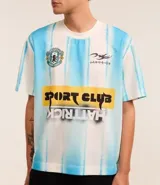 Remera masculina de poliéster con estampa de rayas verticales en celeste y blanco, escudo y lettering "Sport Club Hat Trick".