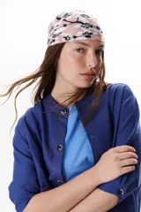 Chaqueta color crudo de lino con cuello redondo, manga tres cuartos, cierre frontal con botones y bolsillos de parche. Detalle de costuras en contraste color marrón.