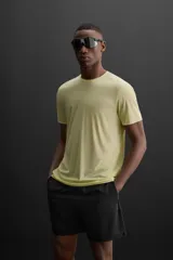 Camiseta deportiva color amarillo claro confeccionada en tejido técnico ligero y elástico. Cuenta con cuello redondo, manga corta, costuras termofijadas y estampaciones reflectantes en la espalda.