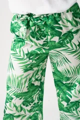 Pantalón palazo verde con estampado de hojas de palmera blancas, cintura elastizada con lazo y corte amplio.