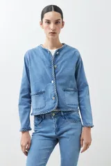 Chaqueta de jean celeste con cuello redondo, cierre con botones metálicos y detalle trenzado en cuello, bolsillos y ruedo.