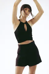 Top blanco de punto acanalado, corte crop, con cuello halter y abertura en el escote en forma de lágrima.