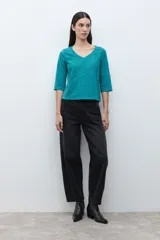 Remera verde petróleo con escote en V, mangas tres cuartos y diseño de broderie calado.