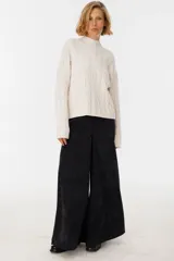 Pantalón negro de corte amplio y alto, con detalles de costura y cierre frontal.