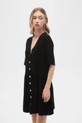 Vestido corto color crema, de corte holgado, con cuello en V y botones frontales.