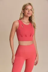 Top deportivo color coral, con cuello redondo y espalda deportiva. Presenta diseño acanalado y pequeñas aberturas decorativas.