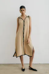 Vestido largo negro sin mangas con cuello camisero y abertura a los costados.