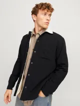 Sobrecamisa negra de manga larga con cuello clásico y fit relajado. Tiene cierre de botones, un bolsillo en el pecho y forro interno de borreguito color crema.