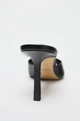 Zapato tipo mule de cuero negro con punta redonda y tacón fino.