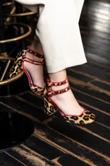 Zapato de tacón con estampado animal print, con doble tira en el tobillo y ribete rojo.