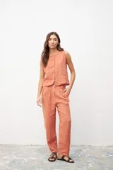 Pantalón de lino color ocre, de corte recto, con pinzas en la cintura y bolsillos laterales. Se combina con un chaleco haciendo juego.