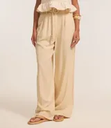 Pantalón pantalona color beige confeccionado en viscolino con viscosa certificada, con cintura con trabillas, cierre tradicional, cinturón de cuerda encapado con hebilla contrastante de adornos, esferas en las puntas y pliegues.