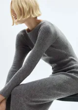 Vestido midi de punto color gris, con cuello barco, manga larga y corte entallado. Incluye cinturón de cuero negro con hebilla plateada.