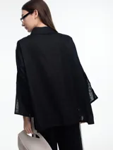 Camisa de lino color negro con silueta amplia y mangas 3/4. Diseño con tiras de color blanco en contraste en la cartera, mangas y cuerpo. Tiene tajos laterales y ruedo irregular en el frente.