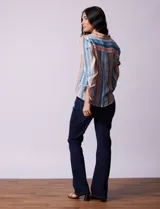 Camisa de gasa estampada a rayas verticales de color celeste, blanco, naranja y marrón. Tiene cuello con solapa, escote en V, abertura central con botones, bolsillo aplicado en el pecho y terminación anudada en la parte delantera.