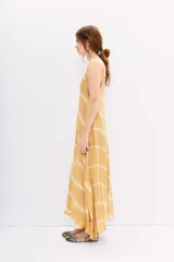 Vestido largo color mostaza con estampado batik, escote en V, breteles finos regulables y corte amplio.