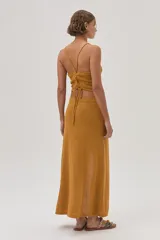 Top halter tejido texturizado en tono mostaza con tiras finas que se atan en la espalda.