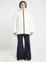 Campera oversize color blanco, confeccionada en nailon suave con un leve brillo. Cuenta con capucha, bolsillos laterales con cremallera, relleno natural y ajuste inferior con cordón. Presenta cierre frontal con cremallera de doble cursor y diseño acolchado.