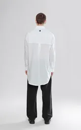 Camisa manga larga blanca de calce oversize confeccionada en textil fresco y liviano, con bolsillo ojal en delantero y cartera escondida.