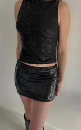 Minifalda negra con lentejuelas, corte ajustado y tiro alto.