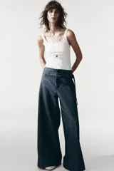 Pantalón de tiro medio azul denim, con trabillas en la cintura y cinturón ajustable con botones. Tiene bolsillos laterales ocultos y pierna ancha.