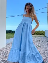Maxi vestido celeste de jean con breteles regulables y bolsillos laterales.