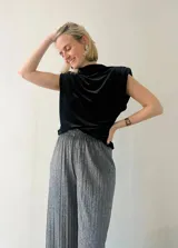 Blusa sin mangas de terciopelo negro con cuello alto y hombreras.