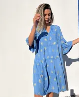 Vestido corto celeste con estampado de hojas doradas, escote en V y mangas 3/4 con volados.
