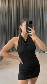 Minivestido negro ajustado al cuerpo, con escote halter y espalda descubierta.