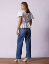 Blusa blanca de algodón con bordado broderie, escote en V con abertura central y botones, cintura elastizada y mangas cortas con terminación elastizada.