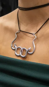 Choker con diseño de serpiente en metal plateado, ajustable con cordón negro.