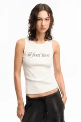 Musculosa blanca de algodón con cuello redondo y estampado frontal con la frase "I feel love" en letras cursivas negras con strass.